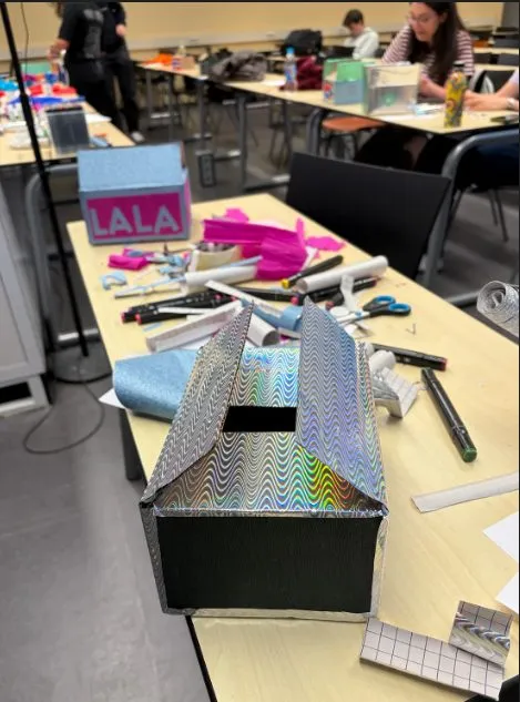A table covered in craft supplies with a half-finished holographic paper project